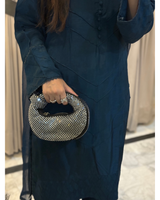 Person wearing a dark blue dress holding a patterned handbag.