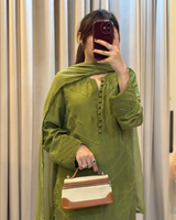 Person wearing a green outfit with a matching scarf, holding a handbag.