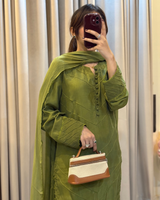 Person wearing a green outfit with a matching scarf, holding a brown and beige handbag.