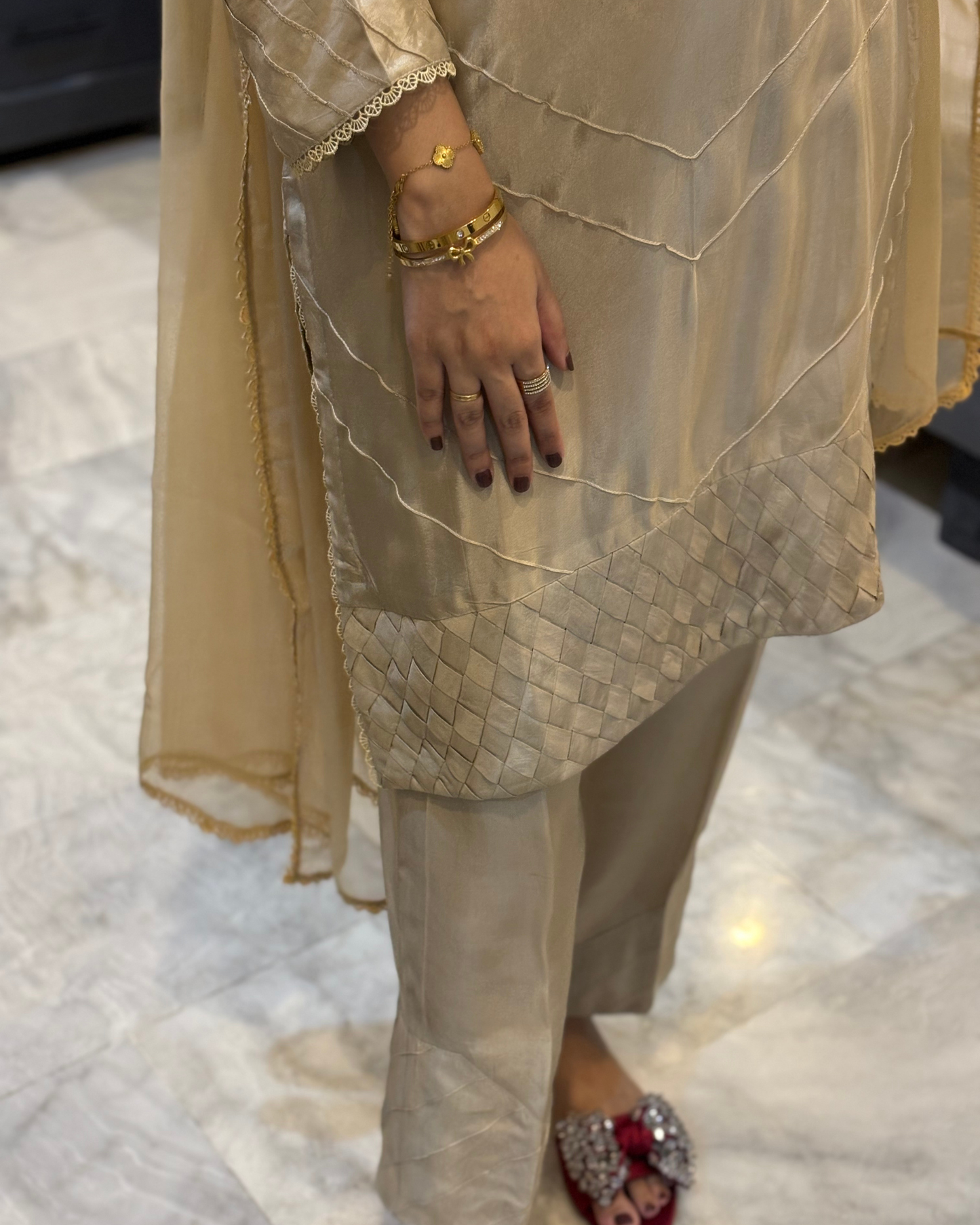Beige traditional outfit with a focus on the hand and jewelry.