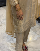 Beige traditional outfit with a focus on the hand and jewelry.