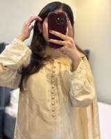 Person wearing a light-colored traditional outfit with intricate designs, taking a mirror selfie.