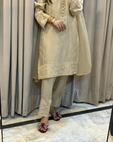 Person wearing a cream traditional outfit with a matching dupatta against a neutral background