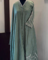 Green dress on a mannequin against a plain background