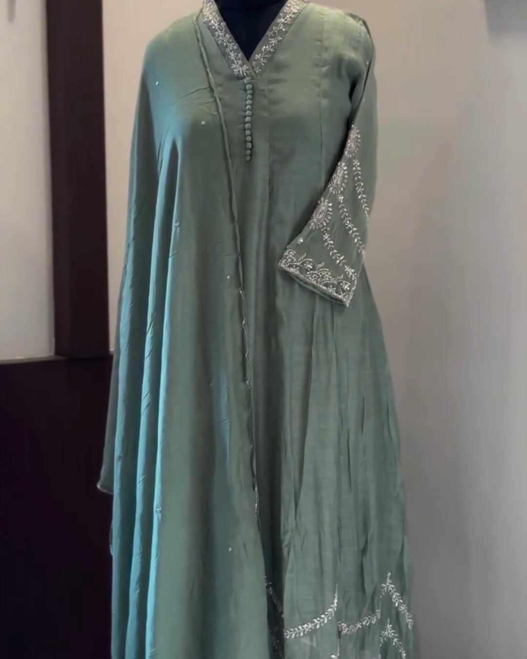 Green dress on a mannequin against a plain background