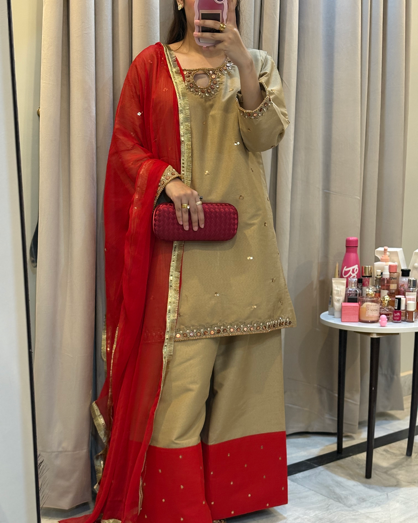 Person wearing a red and beige traditional outfit with a mirror selfie in a room.