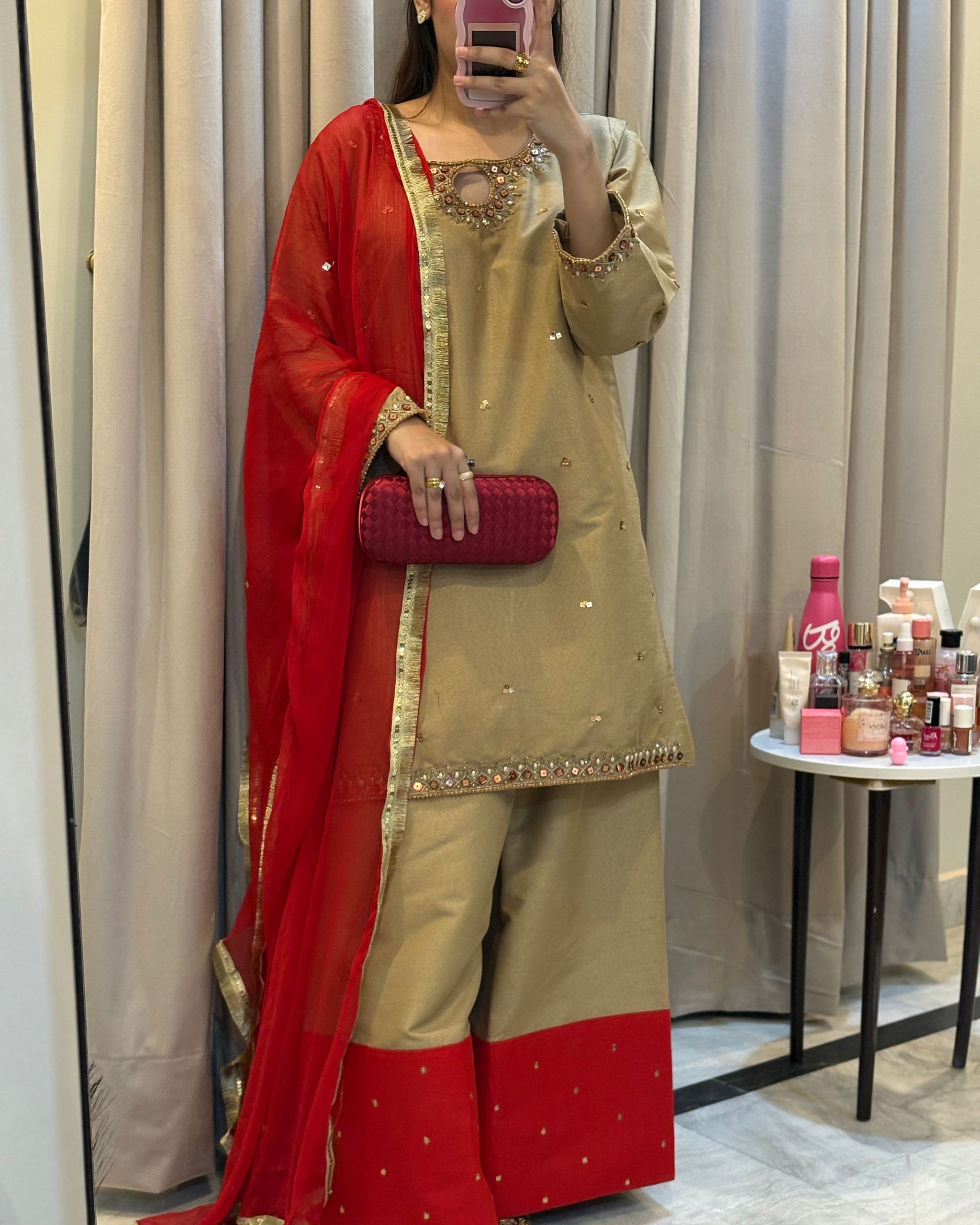 Person wearing a red and beige traditional outfit with a mirror selfie in a room.