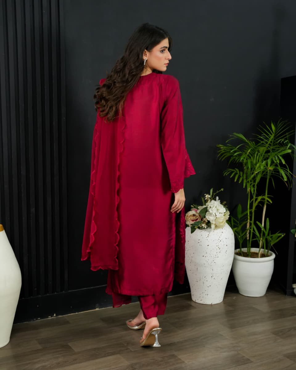 Woman in a red outfit standing in a room with decorative plants and vases.