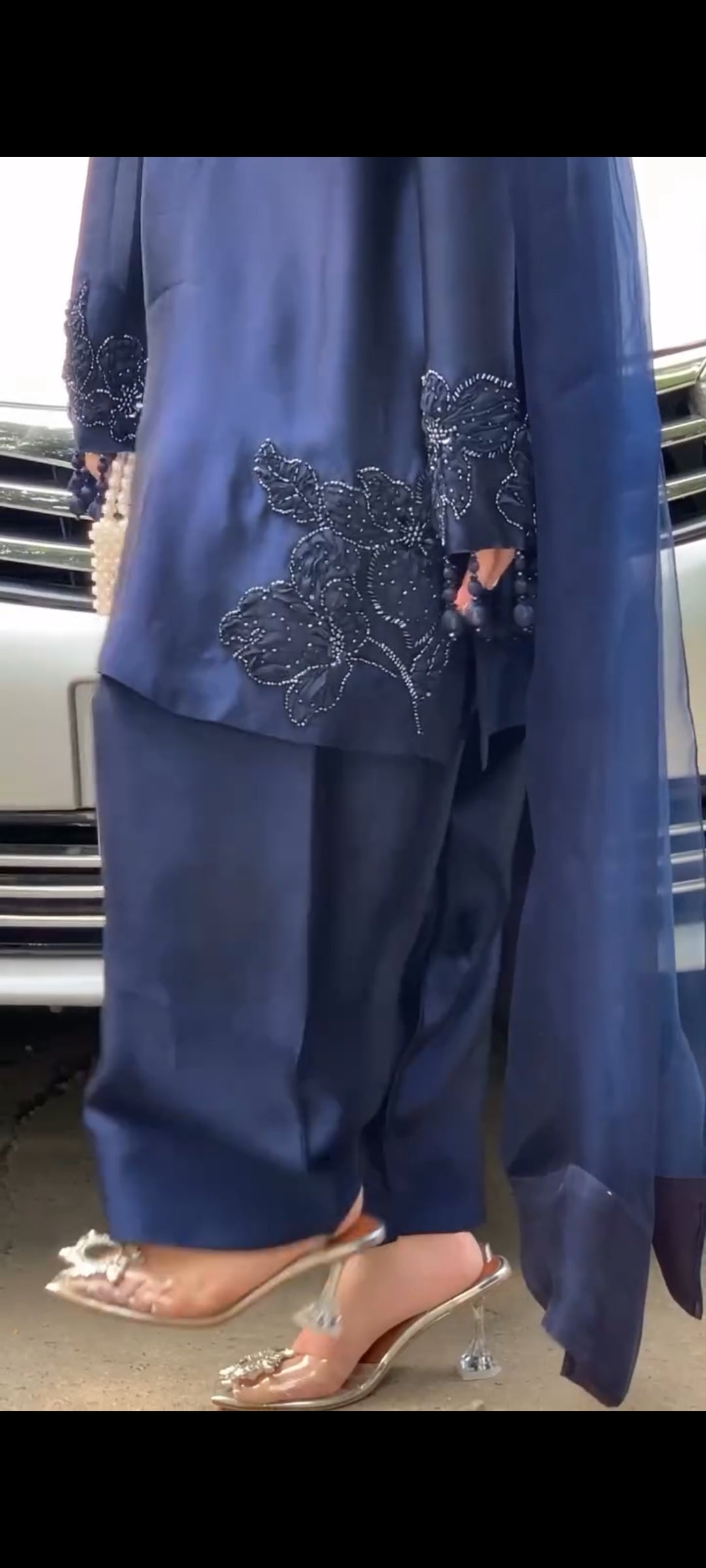 Navy blue outfit with floral embroidery in front of a car