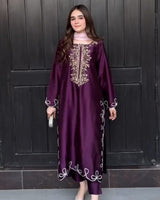 Woman wearing a purple dress with gold embroidery in front of a dark wooden door.