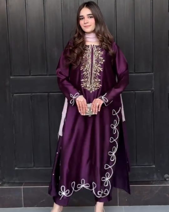 Woman in a purple embroidered dress standing in front of a dark wooden door with text overlay.