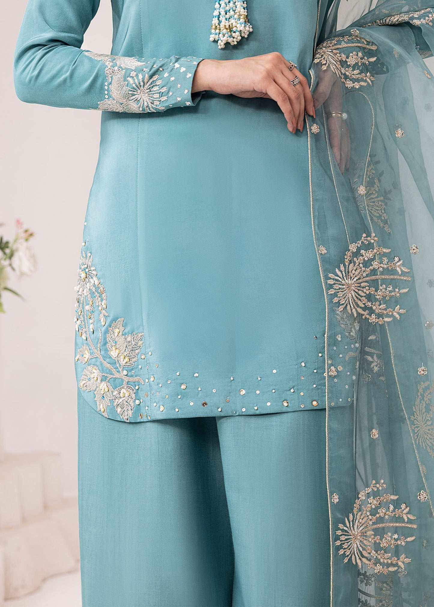 Teal traditional outfit with intricate gold embroidery on a light background